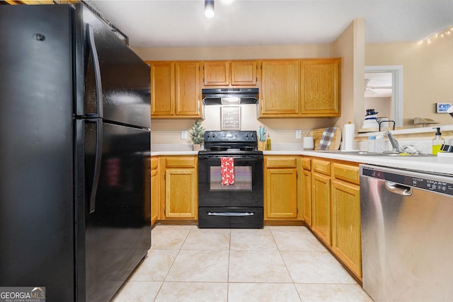 kitchen featuring light tile patterned floors, light countertops, a sink, under cabinet range hood, and black appliances