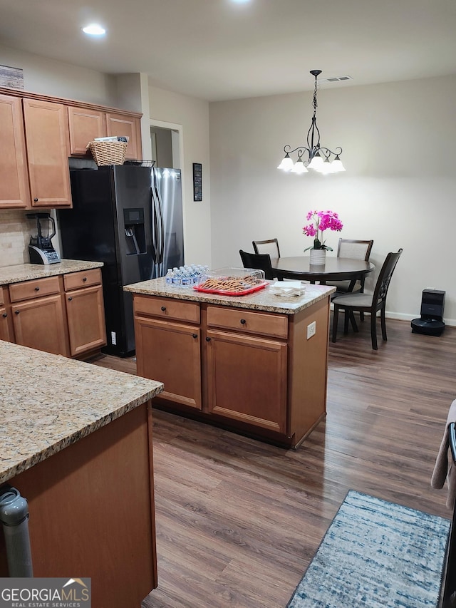 kitchen featuring a kitchen island, refrigerator with ice dispenser, dark wood finished floors, and decorative light fixtures