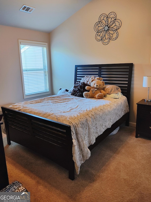 bedroom featuring carpet floors, lofted ceiling, and visible vents