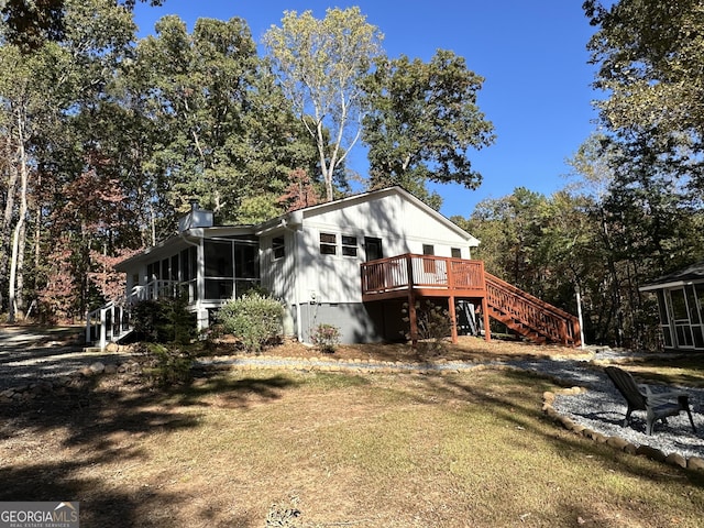 back of property featuring a lawn, a sunroom, and a deck