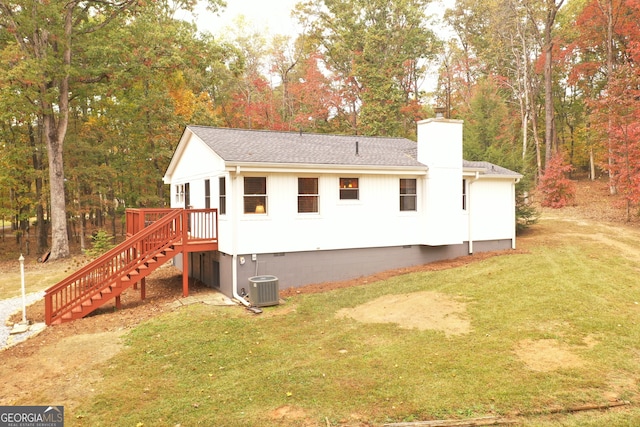 rear view of property featuring a lawn, central air condition unit, and a deck