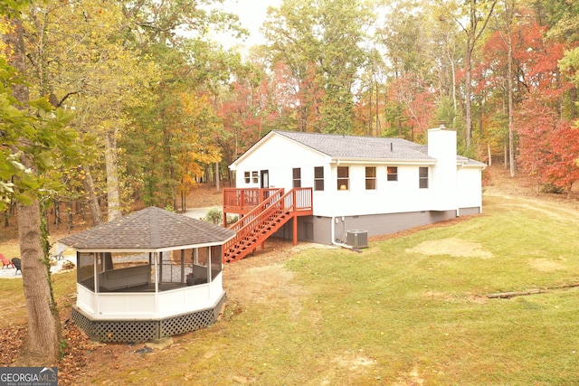 rear view of house featuring a sunroom, a yard, a wooden deck, and central air condition unit