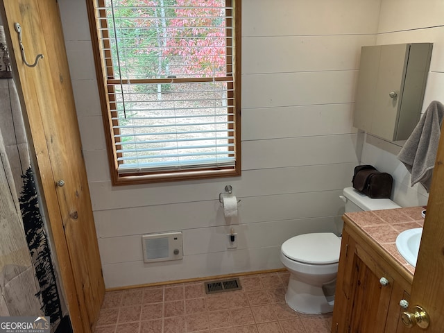 bathroom with vanity, toilet, and wooden walls