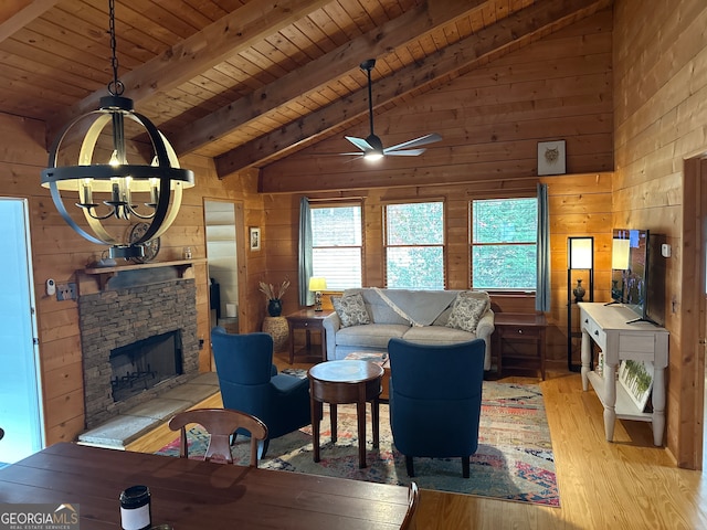 living room featuring vaulted ceiling with beams, wood walls, a fireplace, wood ceiling, and light wood-type flooring