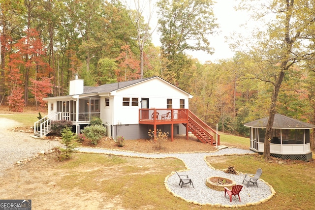 rear view of property with a sunroom, a fire pit, and a deck