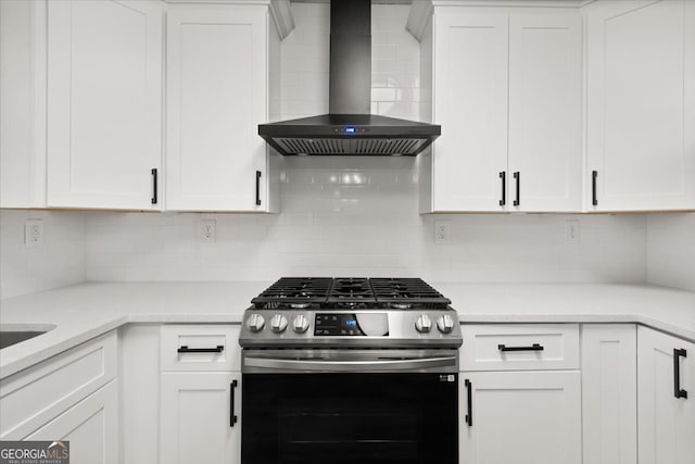 kitchen with white cabinets, decorative backsplash, wall chimney range hood, and stainless steel gas range