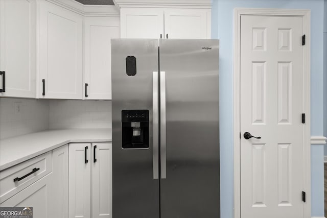 kitchen featuring white cabinetry, backsplash, and stainless steel fridge