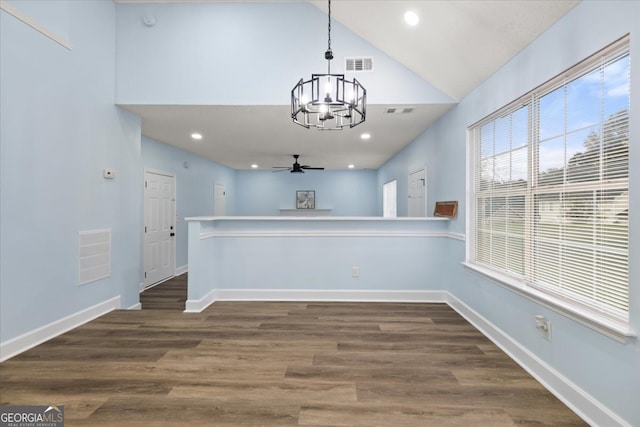 interior space with decorative light fixtures, dark hardwood / wood-style floors, high vaulted ceiling, kitchen peninsula, and ceiling fan with notable chandelier