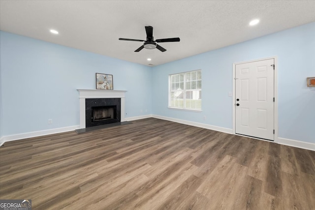 unfurnished living room featuring a textured ceiling, dark hardwood / wood-style flooring, and ceiling fan