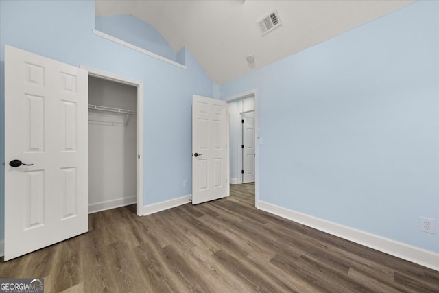 unfurnished bedroom with dark wood-type flooring, a closet, and vaulted ceiling