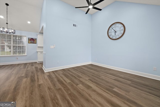 unfurnished room with dark wood-type flooring, high vaulted ceiling, and ceiling fan with notable chandelier