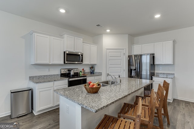 kitchen featuring a center island with sink, sink, white cabinetry, wood-type flooring, and stainless steel appliances