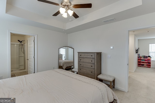 carpeted bedroom with connected bathroom, a tray ceiling, and ceiling fan