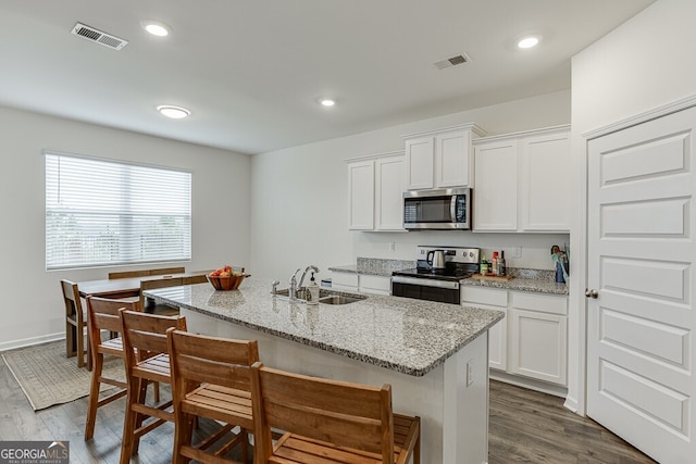 kitchen with stainless steel appliances, sink, dark hardwood / wood-style floors, white cabinetry, and an island with sink