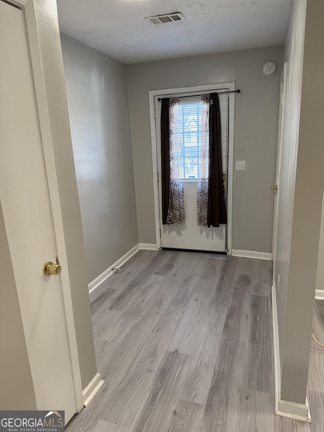 interior space with a textured ceiling and light hardwood / wood-style floors