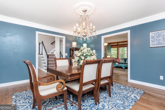 dining space with ornamental molding, wood-type flooring, and a chandelier