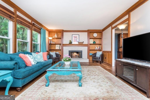 living room featuring a fireplace, built in features, hardwood / wood-style flooring, and crown molding