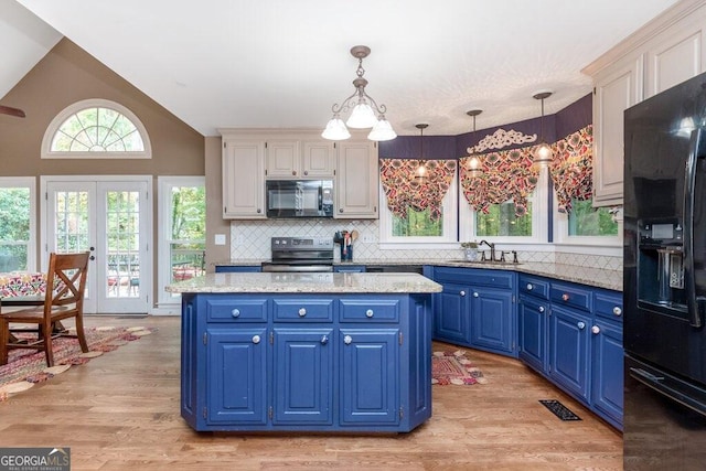 kitchen with black appliances, sink, blue cabinetry, light wood-type flooring, and decorative light fixtures