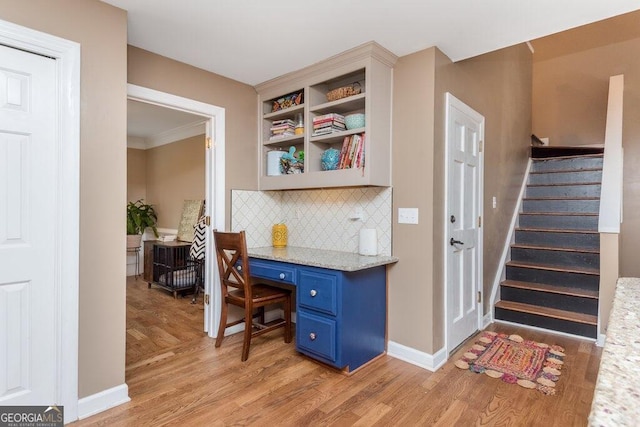 office space with light hardwood / wood-style flooring, built in desk, and crown molding