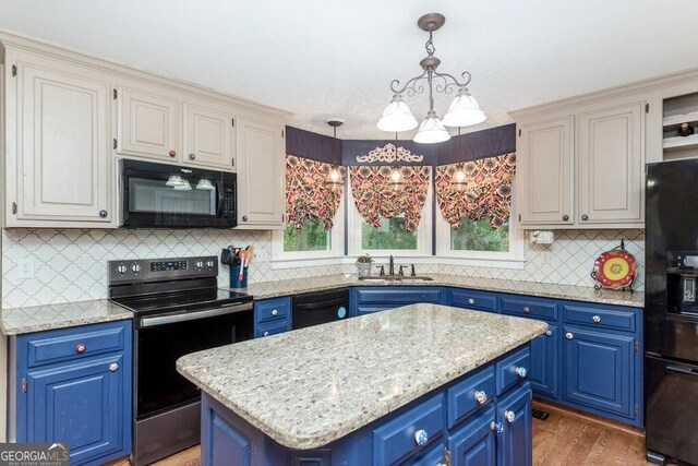 kitchen featuring black appliances, hanging light fixtures, blue cabinetry, a kitchen island, and a notable chandelier