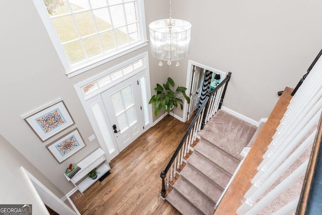 foyer entrance with hardwood / wood-style flooring, a high ceiling, and a notable chandelier