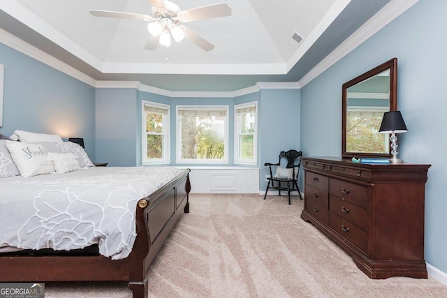 bedroom featuring ceiling fan, light colored carpet, a raised ceiling, and crown molding