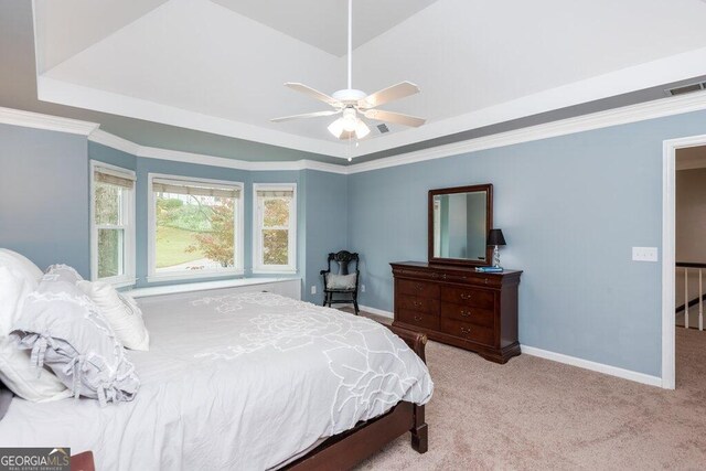 bedroom featuring a tray ceiling, light carpet, ceiling fan, and crown molding