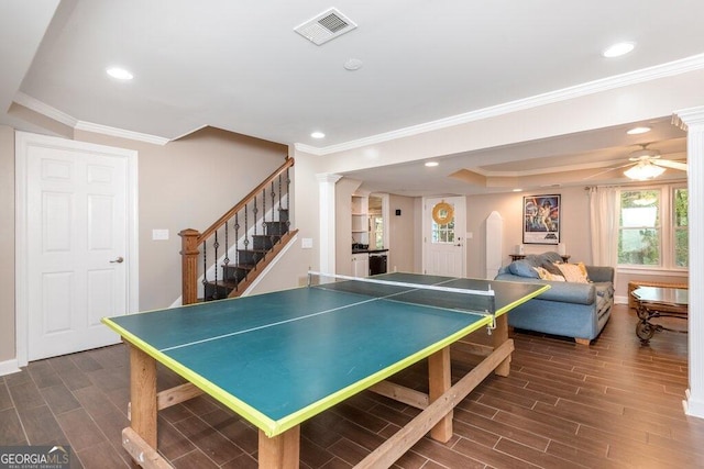 rec room featuring a tray ceiling, crown molding, decorative columns, and ceiling fan