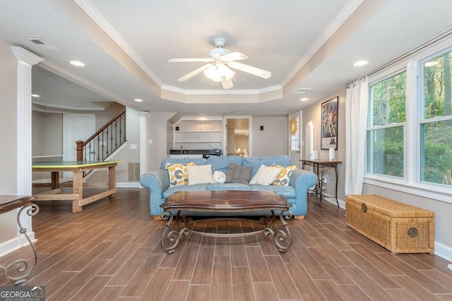 living room with crown molding, hardwood / wood-style flooring, ceiling fan, and a raised ceiling