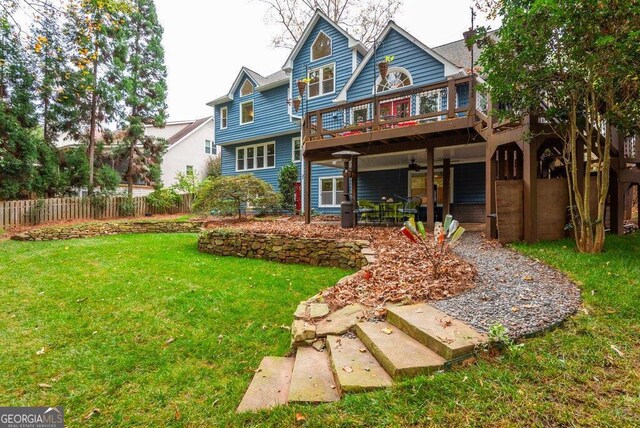 rear view of house featuring a wooden deck, a yard, and a patio area