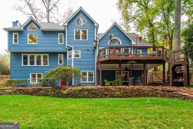 back of house featuring a lawn and a deck