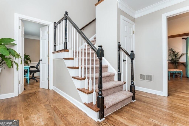 stairway with crown molding and hardwood / wood-style flooring