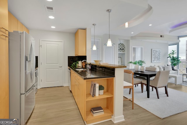 kitchen with kitchen peninsula, light brown cabinets, light wood-type flooring, stainless steel fridge, and pendant lighting