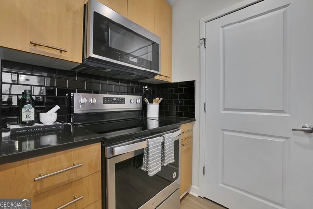 kitchen with decorative backsplash, appliances with stainless steel finishes, and light hardwood / wood-style flooring