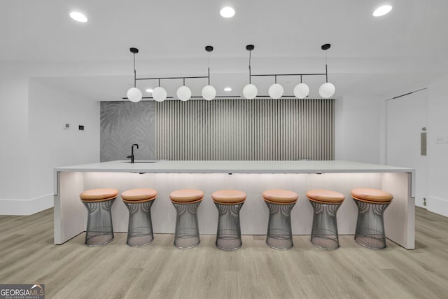 kitchen with a large island, decorative light fixtures, and light hardwood / wood-style flooring