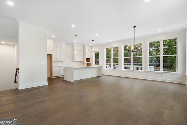 unfurnished living room with a wealth of natural light, dark hardwood / wood-style floors, sink, and a notable chandelier