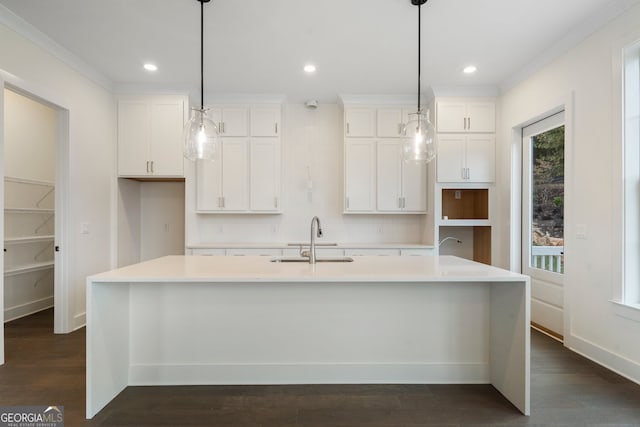 kitchen featuring white cabinetry, sink, decorative light fixtures, a kitchen island with sink, and dark hardwood / wood-style flooring