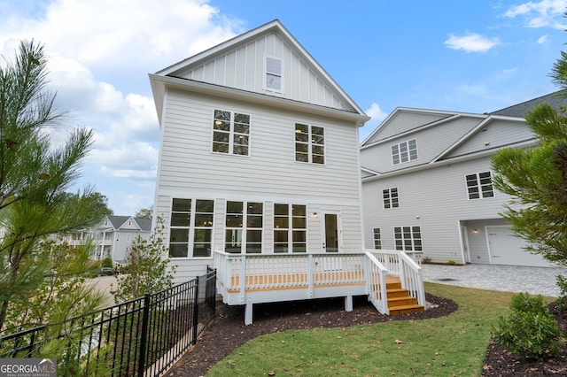 rear view of property with a garage, a yard, and a wooden deck