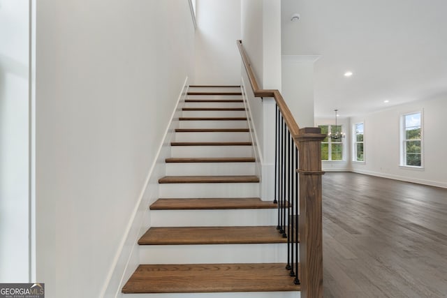 staircase with wood-type flooring and an inviting chandelier