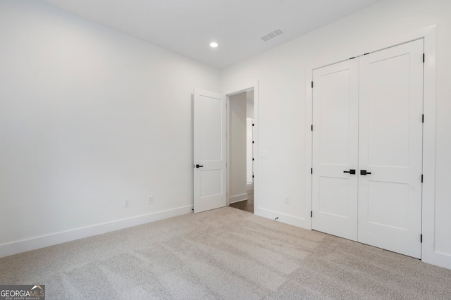 unfurnished bedroom featuring light colored carpet and a closet