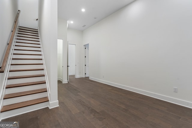 staircase featuring a towering ceiling and wood-type flooring