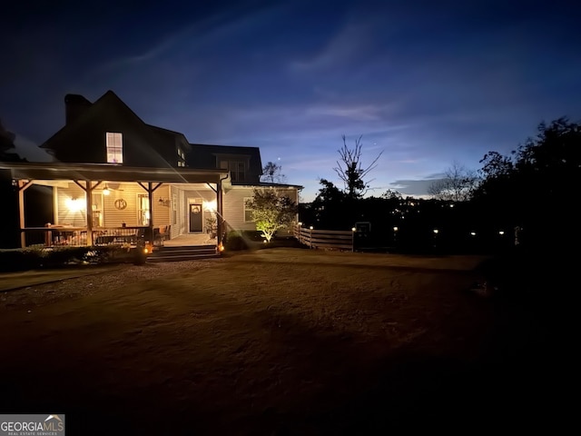 back house at dusk featuring a porch