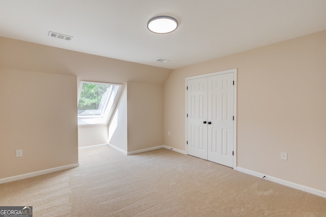 bonus room with light carpet and lofted ceiling with skylight