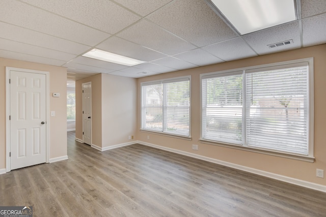 spare room featuring light wood-type flooring and a paneled ceiling