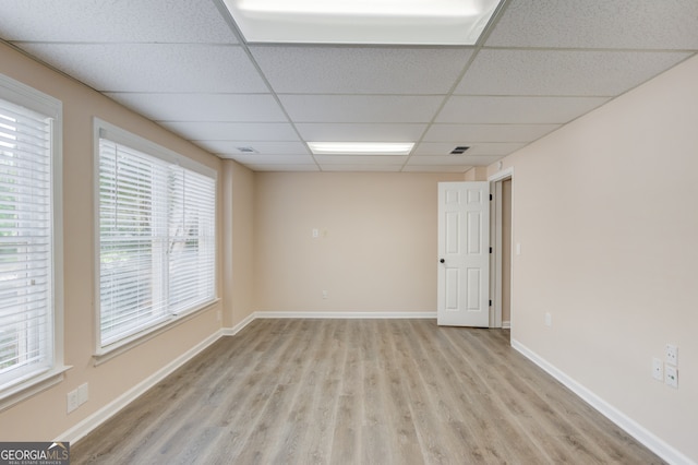 unfurnished room with a wealth of natural light, a drop ceiling, and light hardwood / wood-style floors