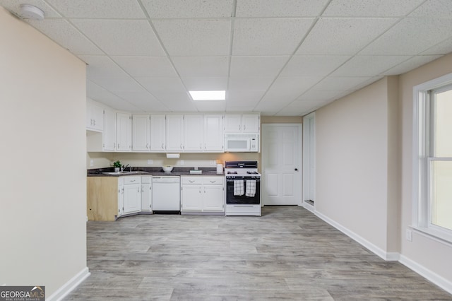 kitchen with white cabinets, light hardwood / wood-style floors, sink, and white appliances