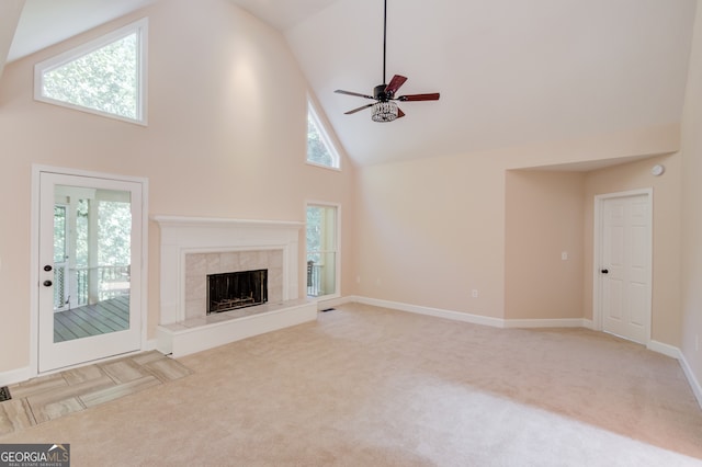 unfurnished living room with a tiled fireplace, a healthy amount of sunlight, and high vaulted ceiling