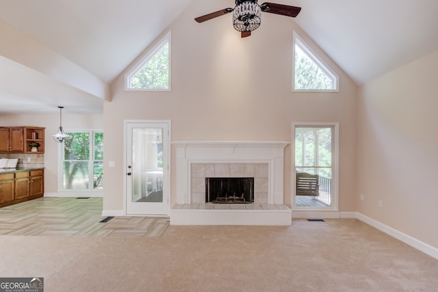 unfurnished living room with high vaulted ceiling, a wealth of natural light, and light colored carpet