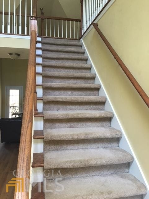 stairs featuring a high ceiling and hardwood / wood-style flooring