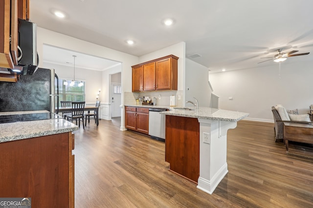 kitchen featuring pendant lighting, appliances with stainless steel finishes, wood-type flooring, and light stone counters